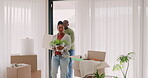 Happy couple, moving in and boxes at home in a room for fresh start. New house, plant and love of black man and woman at a property with commitment, help and support for apartment mortgage or rent