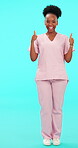 Smile, thumbs up and pointing with a nurse black woman on blue background in studio for healthcare. Portrait, medical and motivation with a happy medicine professional in scrubs for a positive review