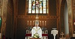 Funeral, church and priest with prayer by coffin for memorial service, sermon and ceremony for death. Religion, guidance and male pastor praying with congregation for comfort with casket in chapel