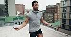 Asian man, fitness and jumping rope on rooftop for workout, cardio exercise or outdoor training in city. Fit, active and sport male person jumping with ropes for healthy body wellness in urban town