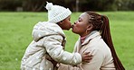 Love, nature and mother kissing her child in park with care for bonding together outside. Nature, happy and African young mom spending time with girl baby kid in outdoor garden for family adventure.