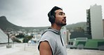 Fitness, headphones and man in city on rooftop for training, workout and exercise outdoors. Sports, motivation and male person listening to music, track or radio for healthy body, wellness and cardio
