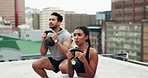 Exercise, people and coach on rooftop with kettle bell, squats and workout in city outdoor. Personal trainer, strength training and motivation of woman and man on roof with sports weight for fitness