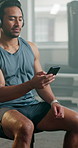 Fitness, headphone and a man with a phone at gym for motivation, streaming and internet. Asian athlete person listening to music, podcast or watch workout video on a smartphone app for exercise
