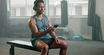 Fitness, phone and a man with headphones at gym for training, streaming and wellness. Asian person listening to music on smartphone for inspiration, motivation and exercise at bench with internet