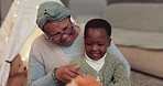 Playing, talking and a grandmother with a child and bear for love, care and bonding in a house. Smile, family and a senior African woman with a boy kid and toys as a gift or for a game together