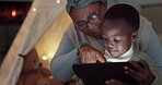 Home, tablet and family with a child at night watching a movie or video for e learning. African woman or grandmother and kid together at fort with tech for education, streaming and e book or story