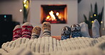 Christmas, socks and cozy family by the fireplace on a sofa in the living room in their home together. Love, kids and parents feet closeup while bonding in the December festive season for celebration