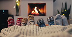 Christmas, socks and family by the fireplace on a sofa in the living room in their home together. Love, children and parents feet closeup while bonding in the December festive season for celebration