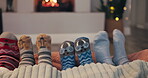 Christmas, socks and family toes by the fireplace on a sofa in the living room in their home together. Love, kids and parents feet closeup while bonding in the December holiday season for celebration