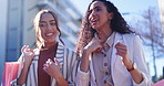 Happy woman, friends and talking with shopping bag in city together about discount, sale or outdoor purchase. Women walking in happiness or conversation from retail deal or promotion in an urban town