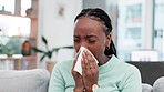 Sneeze, cough and sick black woman with tissue on a sofa for allergies, hay fever or viral infection in her home. Sneezing, bacteria and African female blowing nose in a living room with covid or flu