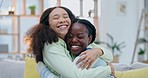 Happy lesbian women, hug and sofa in home with kindness, care or laughing with love, excited or romance. Young gay couple, comic embrace and conversation with smile, reunion and pride on lounge couch