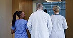 Back, healthcare and doctors walking in a hospital for conversation, teamwork and schedule communication. Diversity, planning and medical employees together at a clinic for wellness strategy