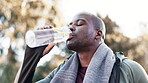 Outdoor, exercise and black man drinking water from bottle in workout, exercise or run in the park, woods or wellness in nature. Liquid, bottle and hydrate in break from training, fitness or sports