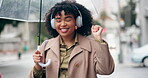 Happy woman, headphones and listening to music in city with umbrella for outdoor audio streaming. Excited female person walking in rain with headset for sound track and dancing in an urban town