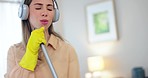 Woman, headphones and music while cleaning, karaoke with radio and housekeeping, mop or broom as microphone. Cleaner, hygiene and energy with audio streaming and house work, dancing and singing