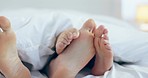 Closeup, playful and feet of a couple in a bed for comfort, intimacy and sleeping with love. House, care and legs of people in the bedroom with a blanket for playing or relax in the morning together