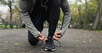 Hands, shoe tie and running outdoor in a park with fitness, workout and exercise for wellness. Person, athlete and feet on a path and road for city marathon and shoes for runner training for health