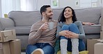 Couple, coffee and new house on floor, talk or relax together in lounge for thinking, idea or fresh start. Man, woman and moving with tea cup, boxes or cardboard package with chat in home living room