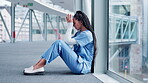 Woman, doctor and headache in mistake, stress or burnout sitting on floor in the hospital building. Frustrated or sad female person or medical healthcare nurse crying in grief, loss or failed surgery