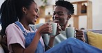 Coffee, talking and a happy black couple on a sofa in the living room of their home together. Tea, love or smile, tea with a man and woman chatting to bond in their house while drinking a beverage