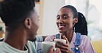 Coffee, conversation and a happy black couple on a sofa in the living room of their home together. Tea, love or smile, tea with a man and woman talking in their house while drinking a beverage