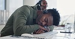 Call center, yawning and tired male consultant in the office sleeping on his desk for rest. Exhausted, burnout and overworked young African man customer service agent taking a nap in the workplace.