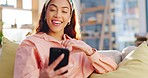 Video call, phone and young woman in the living room talking and blowing a kiss for greeting. Communication, technology and female person from Colombia on virtual conversation on a sofa in apartment.