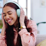 Headphones, dancing and young woman on a sofa listening to music ...