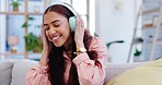 Headphones, dancing and young woman on a sofa listening to music, playlist and album in the living room. Happy, smile and female person moving and streaming a song or radio in the lounge at her home.