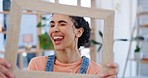 Funny, face and a woman with a picture frame in a house with a smile, crazy expression and tongue out. Happy, comic and portrait of a young girl or person with a decoration for a photo in a lounge