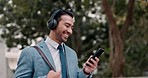 Headphones, phone and businessman walking in the city listening to music and networking on social media. Happy, smile and professional male person streaming playlist with cellphone commuting in park.