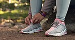 Hiking, forest and hands tie shoes outdoors for workout, exercise and walking in nature or woods. Travel, fitness and closeup of person with sneakers on ground for adventure, journey and trekking