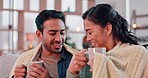 Coffee, happy and couple with blanket on sofa for bonding, relax and cozy in living room with fire. Love, dating and man and woman with hot drink in mug in conversation, talking and speaking at home