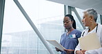 Doctor, documents and nurse walking, talking and communication in hospital lobby. Folder, people and medical professional in discussion for healthcare project, wellness and conversation in clinic