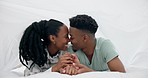 Black couple, bed and kiss with happy love under a bedroom blanket in the morning at home. Smile, funny and young people relax together with support and care in house with commitment and romance