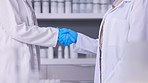 Doctor, scientist and handshake in meeting, partnership or teamwork together at the laboratory. Closeup of people, healthcare or medical professional and science team shaking hands in greeting at lab