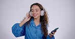 Woman, headphones and dance with smartphone in studio to celebrate freedom, party and audio on white background. Happy young model dancing with cellphone, listening to music and hearing radio sound 