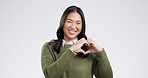 Heart, hands and woman face in studio for thank you, happy and kindness gesture on white background. Smile ,portrait and asian female model with emoji for love, vote or hope finger frame for support