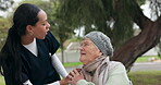 Nurse, elderly care and talking to patient on wheelchair in nature, support or trust in assisted living at park. Female caregiver listening to senior person with a disability in healthcare retirement