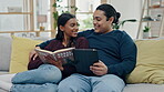 Couple, tablet and reading a book on a home sofa for search, internet and knowledge or relax. Happy man and woman together on couch with technology and novel for entertainment, learning or connection