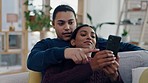 Couple, phone and talking on a home sofa for search, internet and social media. Happy man and woman relax and laugh together on couch with a smartphone for funny video or pointing at choice online