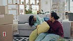 New home, pillow fight and couple on sofa, happy and bonding in living room, apartment or property. Funny, man and woman play with cushion on moving day, relocation and intimate in real estate house