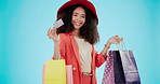 Happy, woman and a credit card for shopping on a blue background and excited about retail bags. Face, ecommerce and portrait of a girl with a smile from fashion discount, payment and a clothes sale