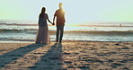 Sunset, man and woman on beach holding hands and walking on sand in summer for date, vacation and happiness. Love, sea and people in nature on holiday in Thailand for anniversary and romance 
