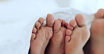 Couple, relax and feet in bed together on holiday, vacation or sleeping in the morning with love, comfort and playful touching. People, care and playing with foot under blanket in bedroom or home