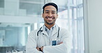 Man, face and doctor with arms crossed in hospital for healthcare services, surgery and clinic consulting. Portrait of happy asian surgeon, expert therapist or medical professional working with trust
