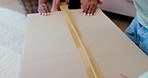 Closeup, hands and closing a box for moving, real estate or help with relocation to new home. Zoom, house and people with tape for property, packaging or storage of cardboard in an apartment