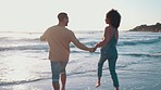 Beach, holding hands and couple with sunset, running and travel with tropical adventure, playful or vacation. People, man or woman with seaside holiday, water or love with romantic getaway and energy